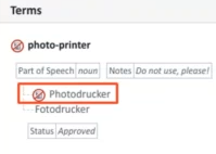 Trados Studio termbase entry showing the term 'photo-printer' with a forbidden term 'Photodrucker' highlighted in red and marked with a prohibition sign, indicating not to use it.