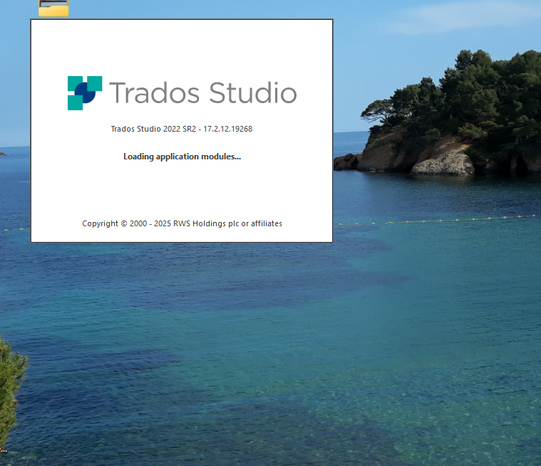 Trados Studio 2022 SR2 loading screen with the text 'Loading application modules...' displayed over a background of a scenic ocean view with trees and rocks.